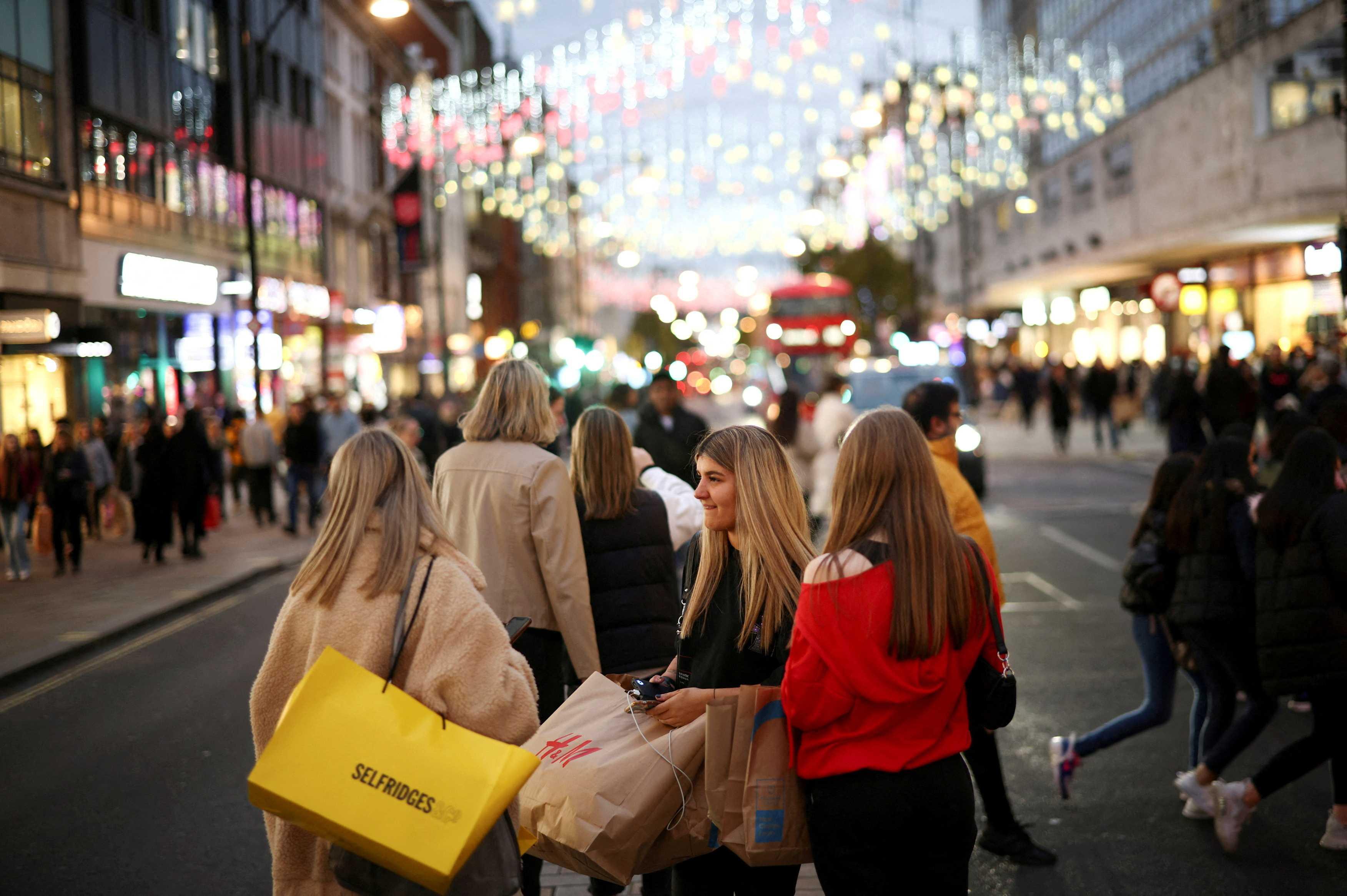 People with shopping bags walk along Oxford Street illuminated with Christmas lights in London, Britain, Nov 13, 2021. Photo: Reuters