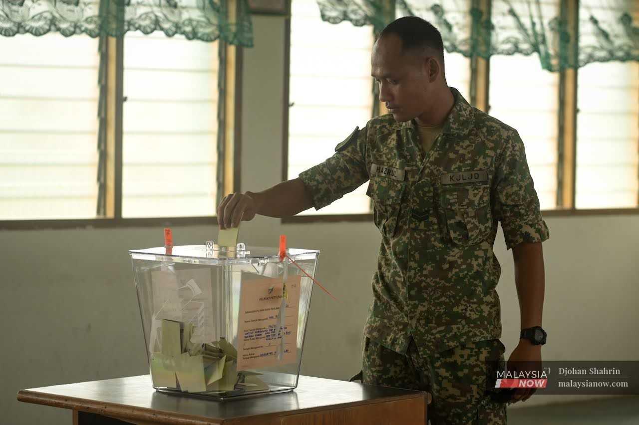 Seorang pegawai tentera memasukkan kertas undi yang telah dipangkah ke dalam peti undi di kem tentera Sungai Besi.
