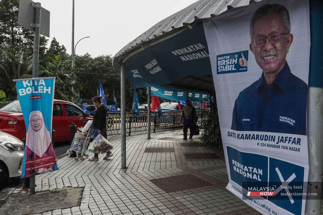 Poster featuring Pakatan Harapan's Dr Wan Azizah Wan Ismail and Perikatan Nasional's Kamarudin Jaffar hang along a walkway near the Sri Kota flats in Bandar Tun Razak.  
