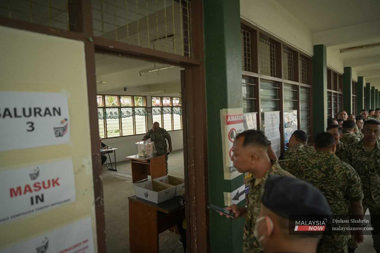 An army officer casts his ballot for the Bandar Tun Razak parliamentary seat at the Sungai Besi camp as others wait for their turn. 