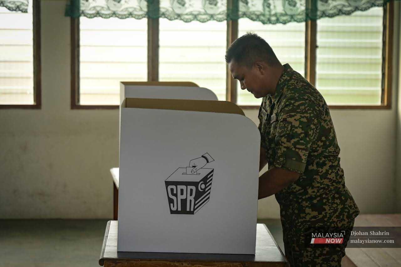 An army man stands at a polling booth as he casts his ballot in early voting. 