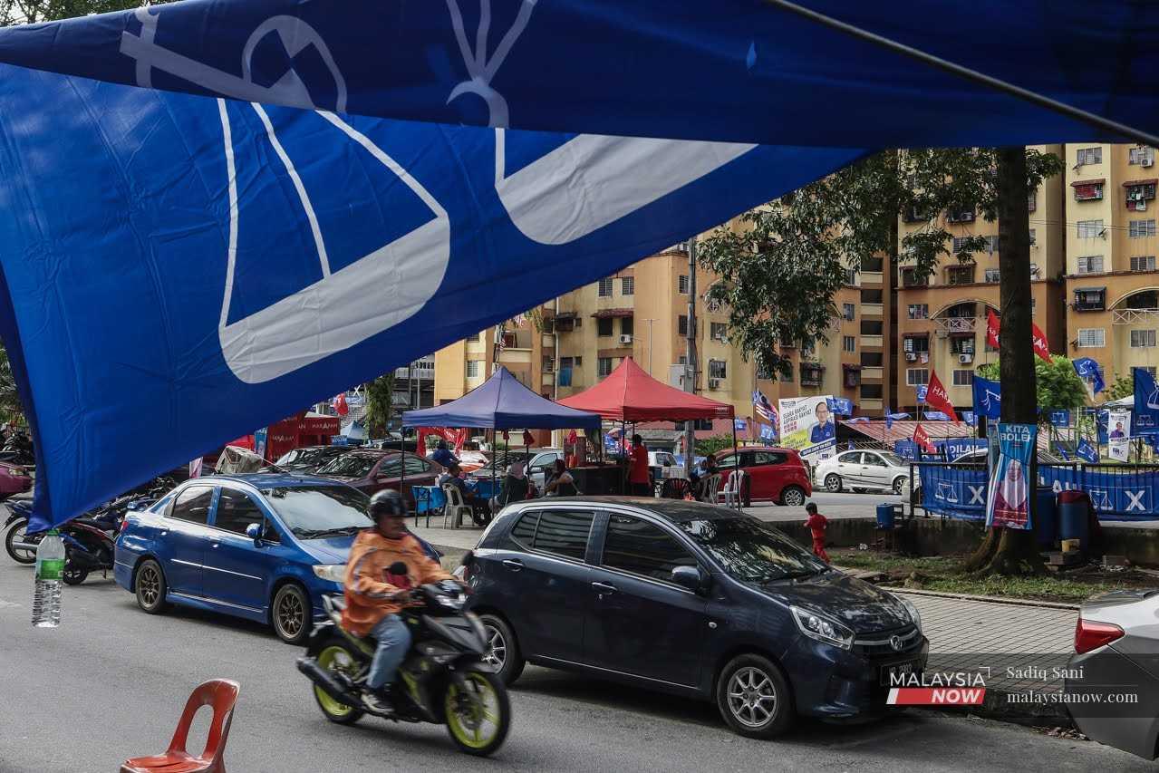 A Barisan Nasional flag billows overhead as traffic passes the Sri Kota flats in Bandar Tun Razak, Kuala Lumpur. 
