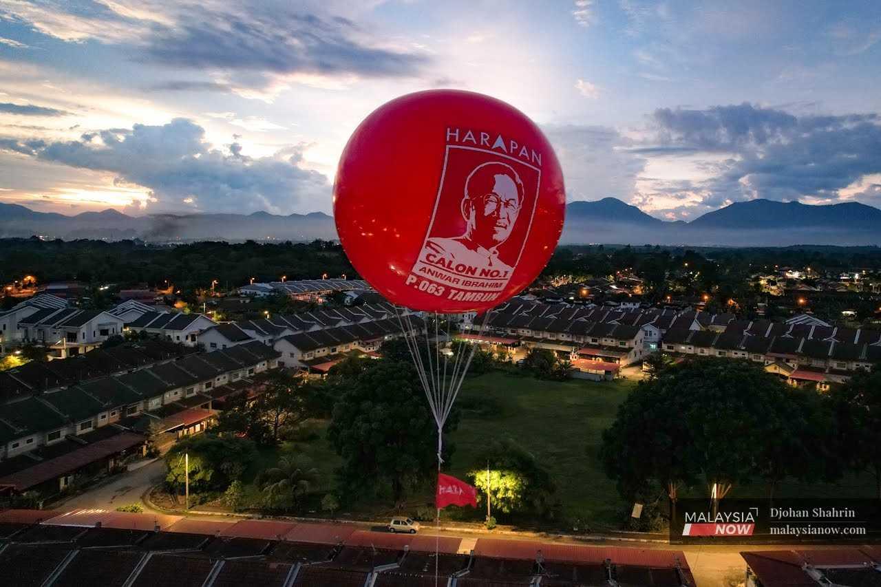 A huge balloon bearing the image of Anwar floats in the sky near a housing area near Tambun town. 