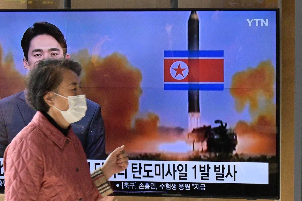 A woman walks past a television showing a news broadcast with a file photo of a North Korean missile test, at a railway station in Seoul on Nov 17. Photo: AFP