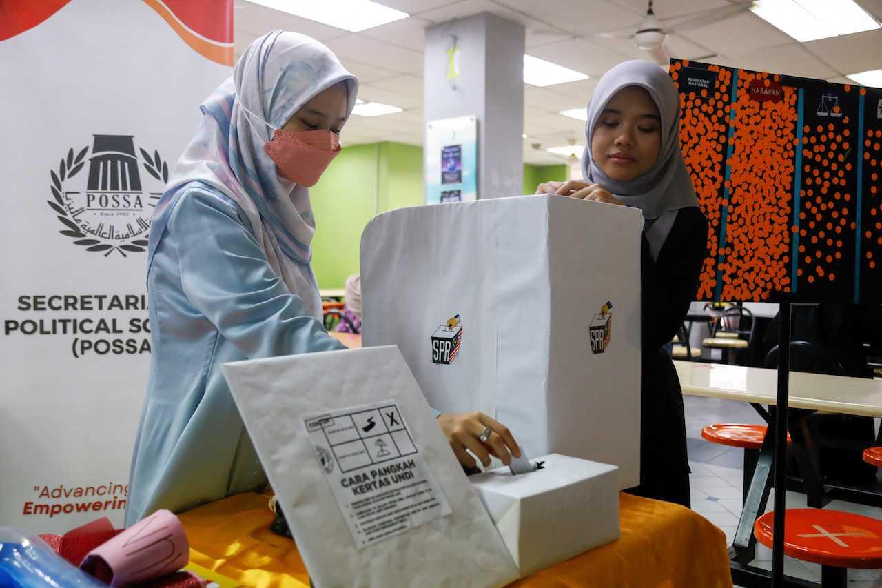 Hajar Wahab helps a fellow undergraduate cast a vote during a mock-up election to familiarise the first-time voter with the election procedure at the International Islamic University Malaysia in Gombak, Selangor. Photo: Reuters
