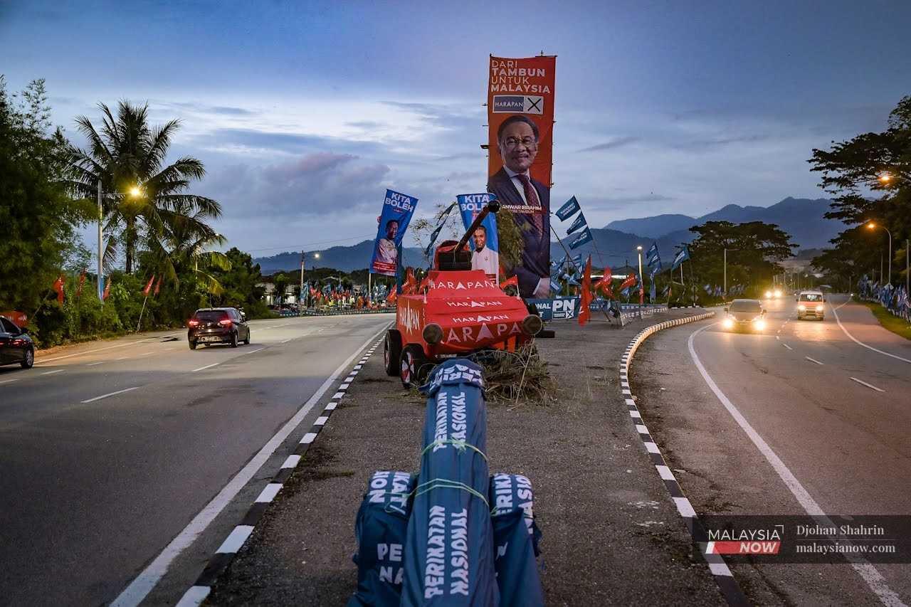 A replica of a cannon, draped in Perikatan Nasional flags, faces a tank decked out in Pakatan Harapan flags at the main road heading to Hulu Kinta. 