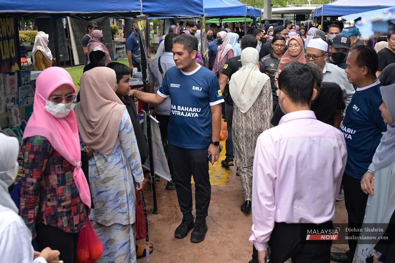 Radzi greets voters during a walkabout as part of his campaign at the communications and multimedia ministry in Presint 2, Putrajaya. 