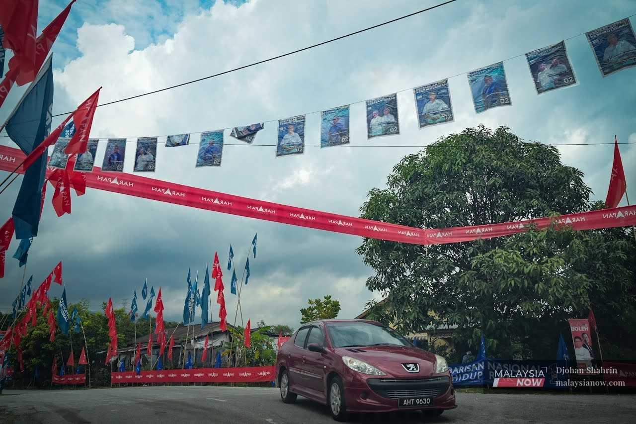 A car passes below banners and flags put up around Tambun in Perak ahead of the election on Saturday.