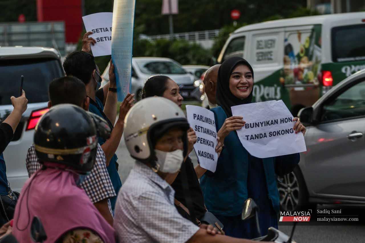 Nurul Fadzilah Kamaluddin holds up a sign during a flash mob in Setapak, during the campaign period ahead of the election. 
