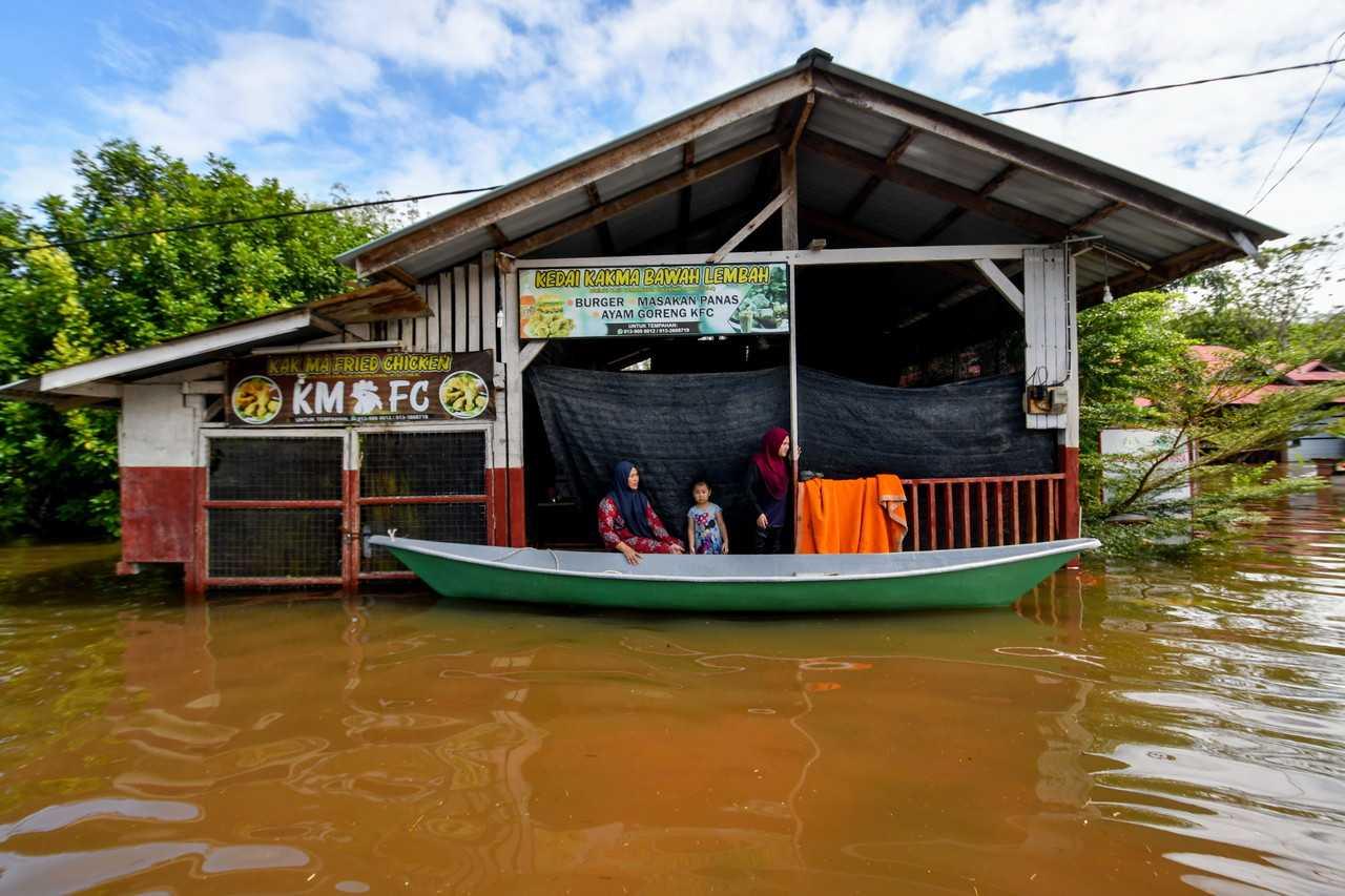 Residents travel by boat to check on a shop that was partially submerged in the flood that hit their village in Rantau Panjang, Pasir Mas, on Nov 13. Photo: Bernama