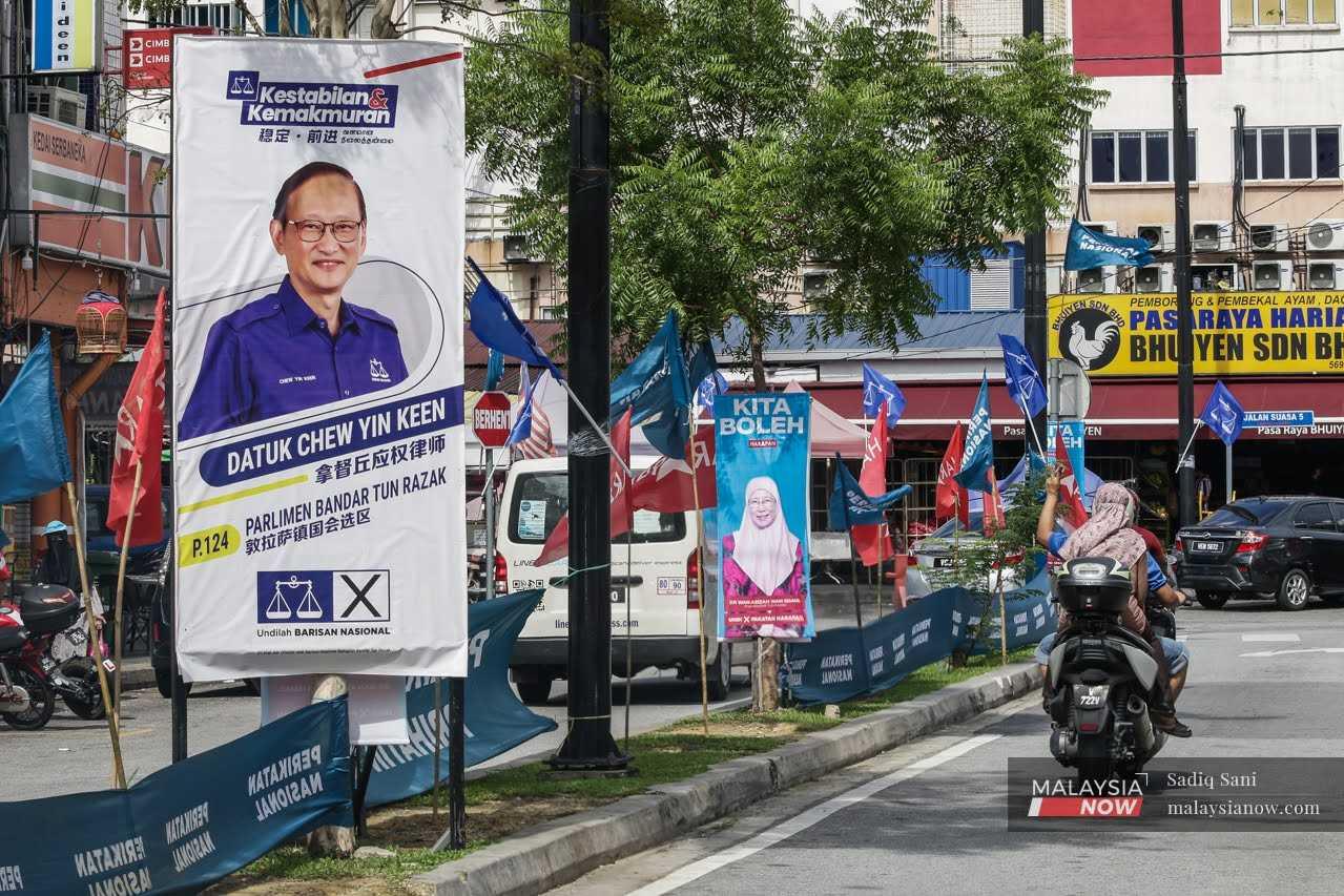 Traffic passes beside posters of election candidates for the Bandar Tun Razak seat in Sungai Besi, Kuala Lumpur.