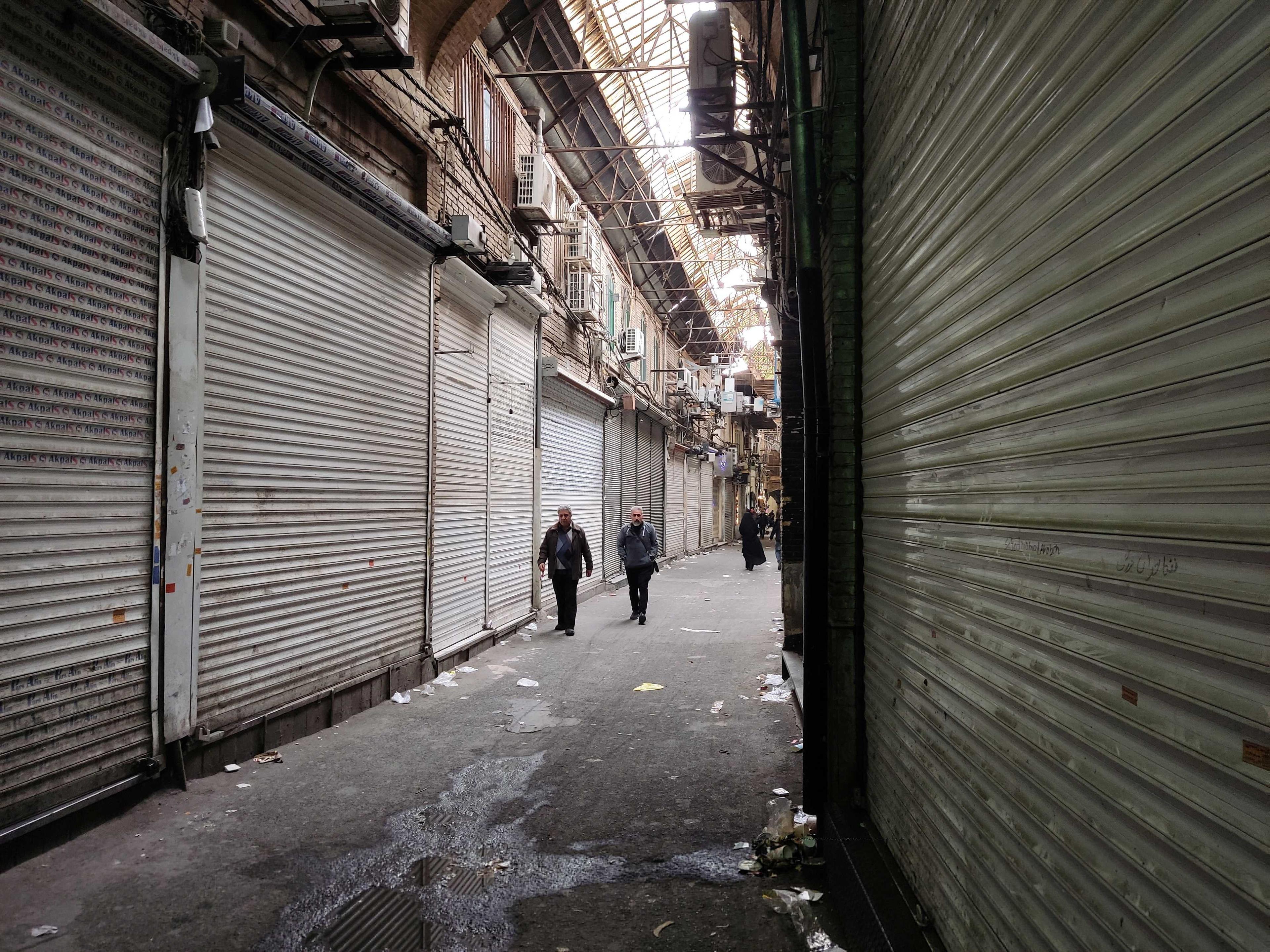 People pass shops which were closed following the recent riots and the call of protesters to close the markets, in Tehran Bazaar, in Tehran, Iran, Nov 16. Photo: Reuters