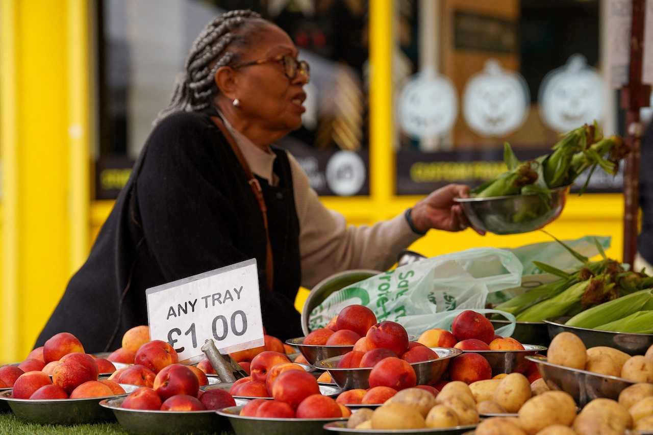 A woman shops for food items at a market stall in London, Britain, Sept 30. Photo: Reuters