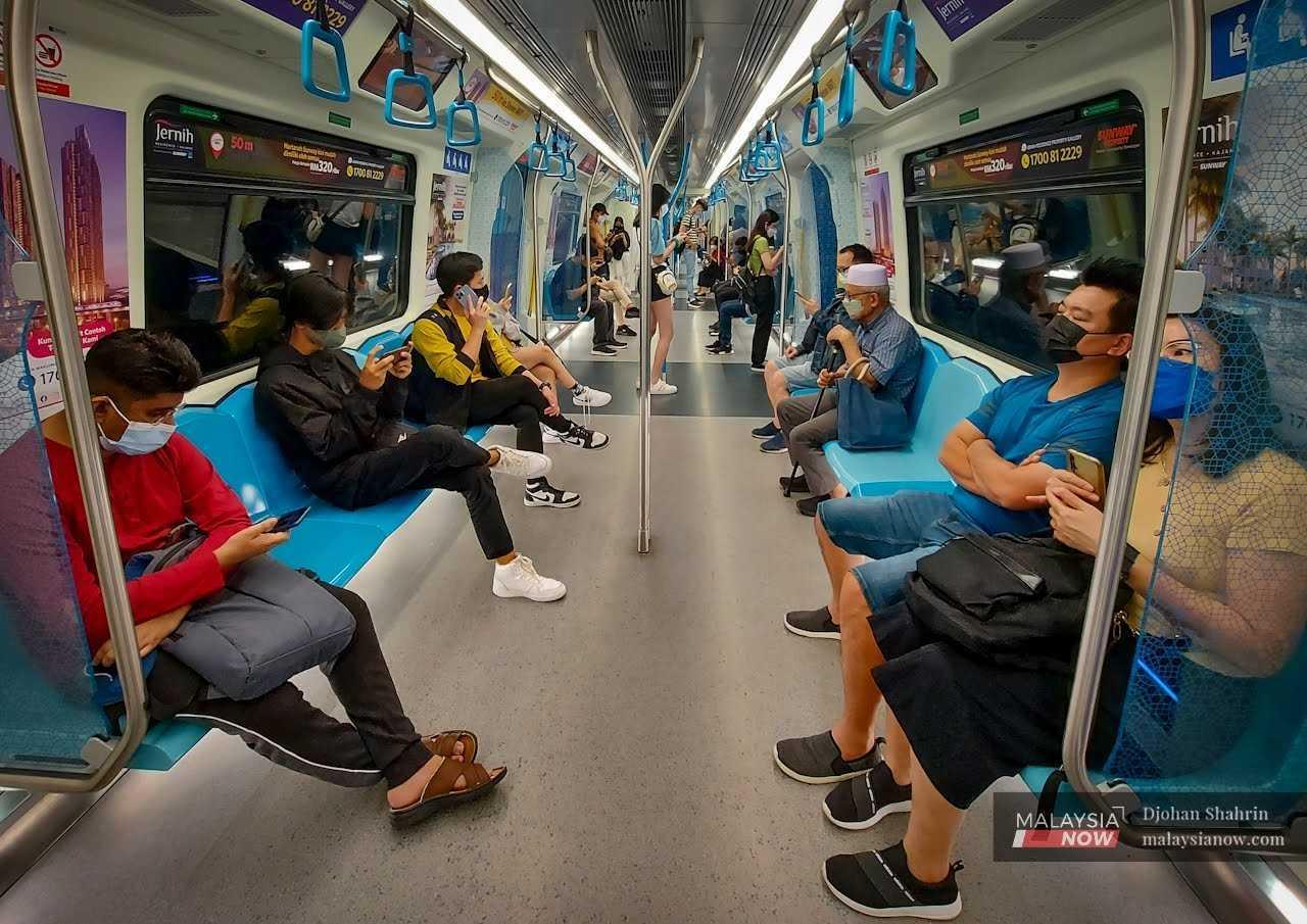 Commuters wearing face masks sit in an MRT on the Cheras-Damansara line.