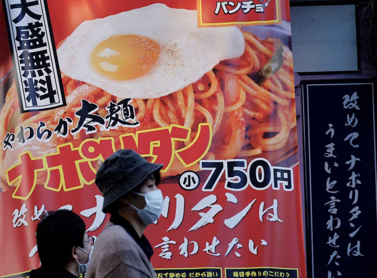 People walk past a signboard of a restaurant at a shopping district in Tokyo, Japan, Oct 28. Photo: Reuters
