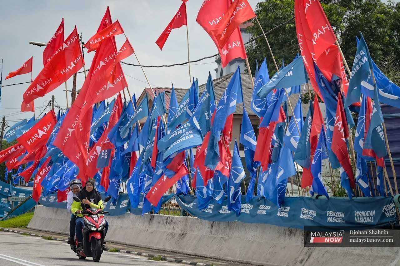 Motorcyclists pass an army of party flags along a main road in Tambun, Perak.