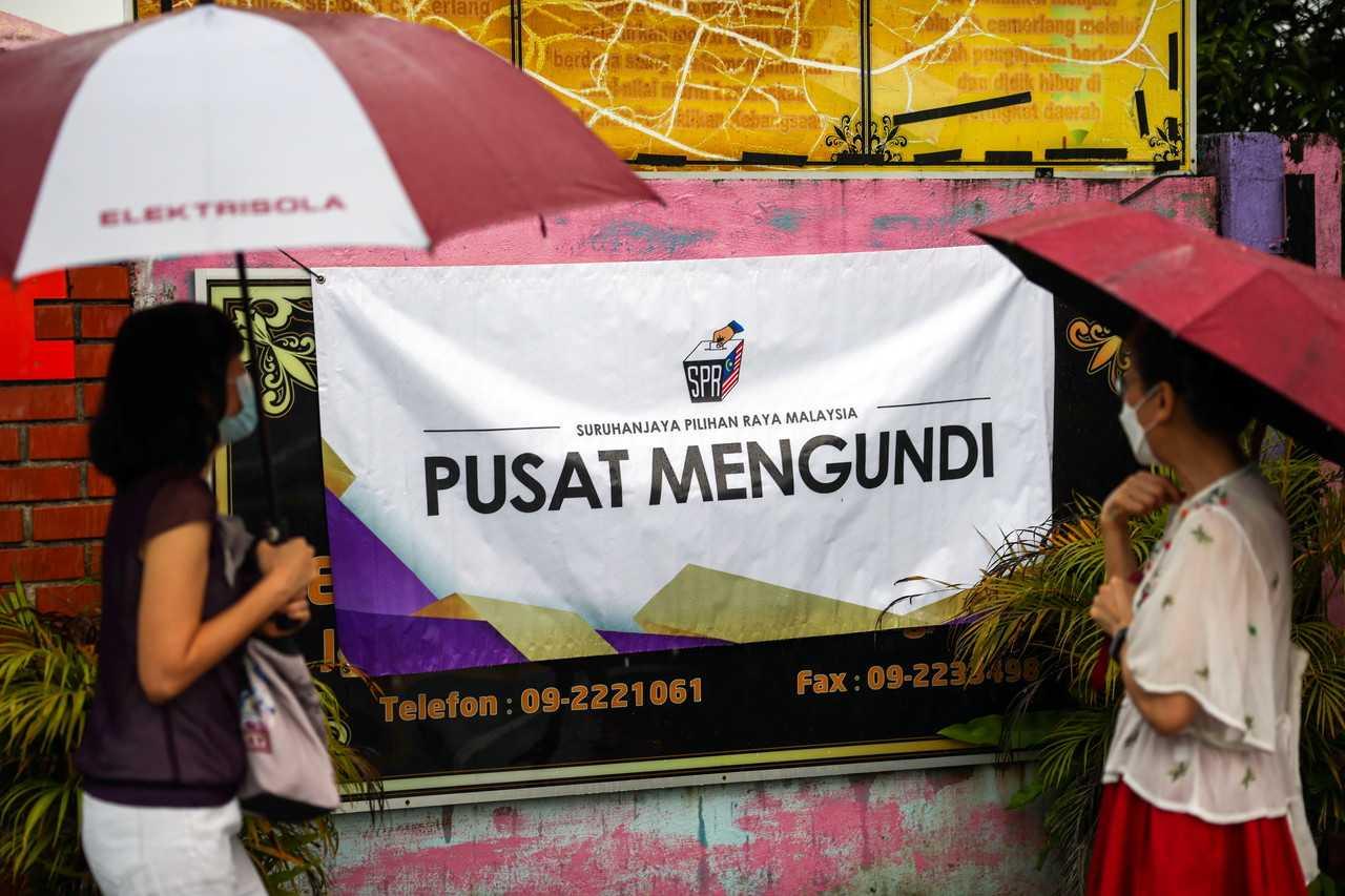 Voters shield themselves from the rain with umbrellas at the SK Sulaiman polling centre in Bentong. Photo: Bernama