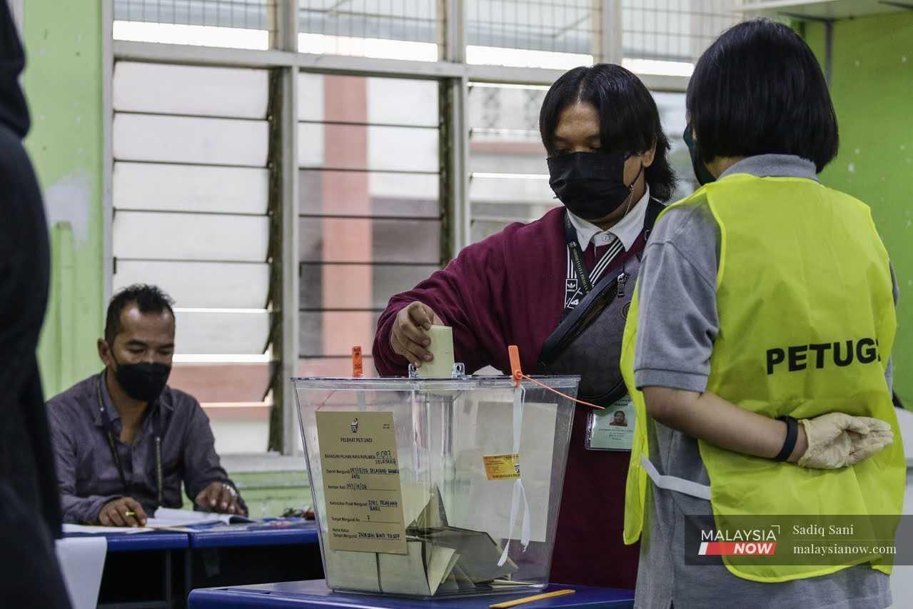 Seorang lelaki memasukkan kertas undi ke dalam peti undi di pusat pengundian di Selayang, Selangor.