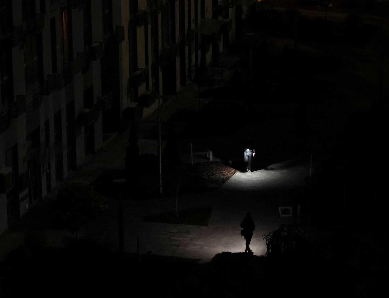 Residents light their way as they walk in the yard of an apartment building during a power outage after critical civil infrastructure was hit by Russian missile attacks in Ukraine, in Kyiv, Ukraine, Nov 9. Photo: Reuters