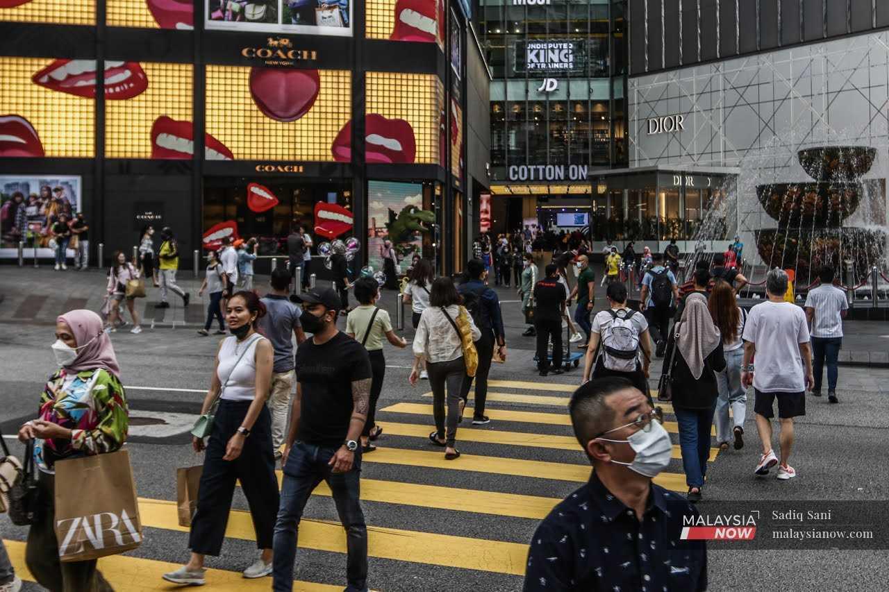 Pedestrians cross a road in the shopping district of Bukit Bintang in Kuala Lumpur.