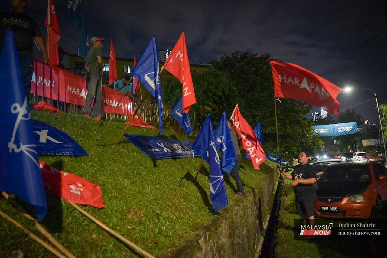 Sukarelawan parti mengibarkan bendera Pakatan Harapan di sebelah bedera Barisan Nasional menjelang pilihan raya Sabtu lalu di Kuala Lumpur.