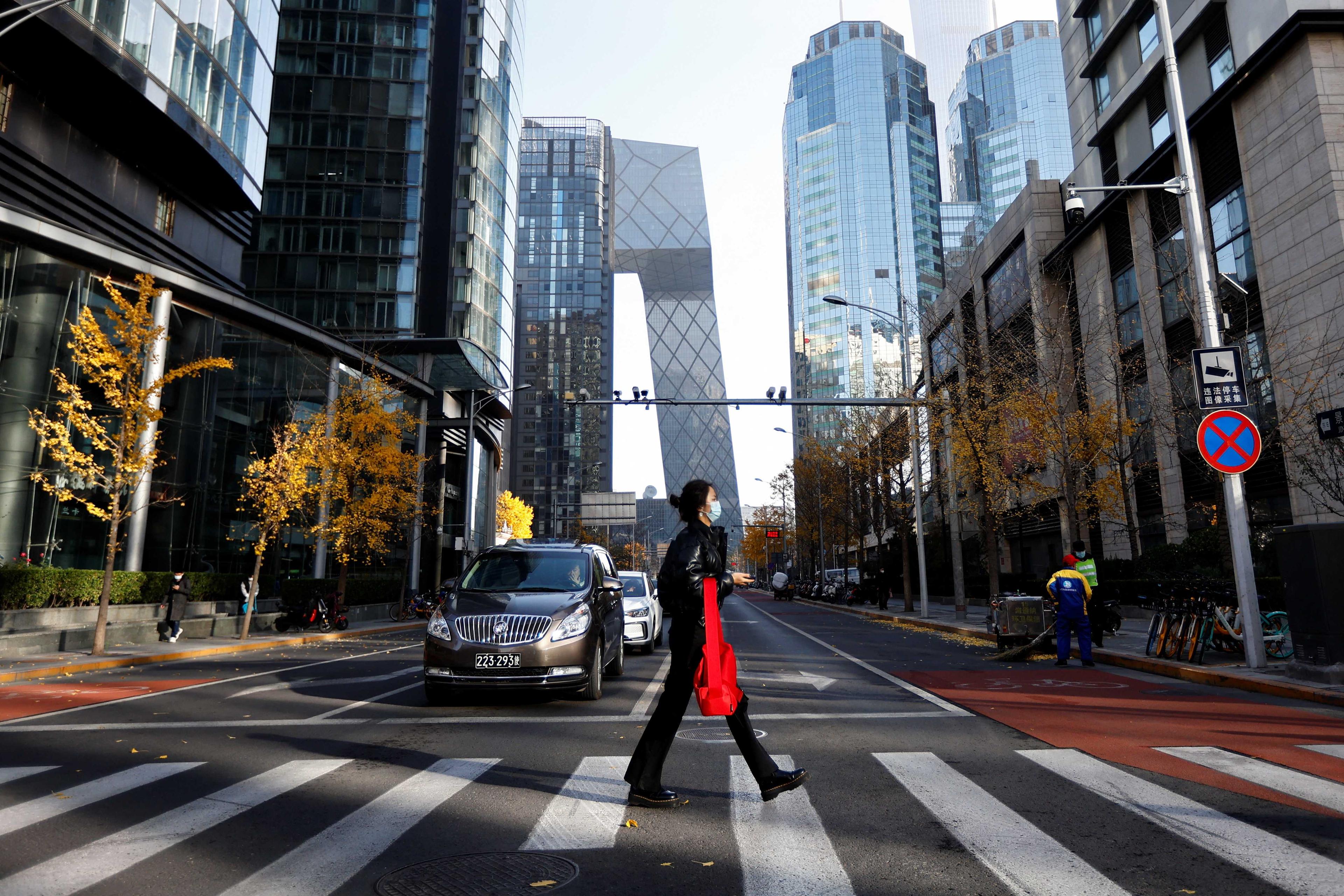 A woman walks across the street during morning rush hour, following the outbreak of Covid-19, in the Central Business District in Chaoyang District, Beijing, China Nov 21. Photo: Reuters