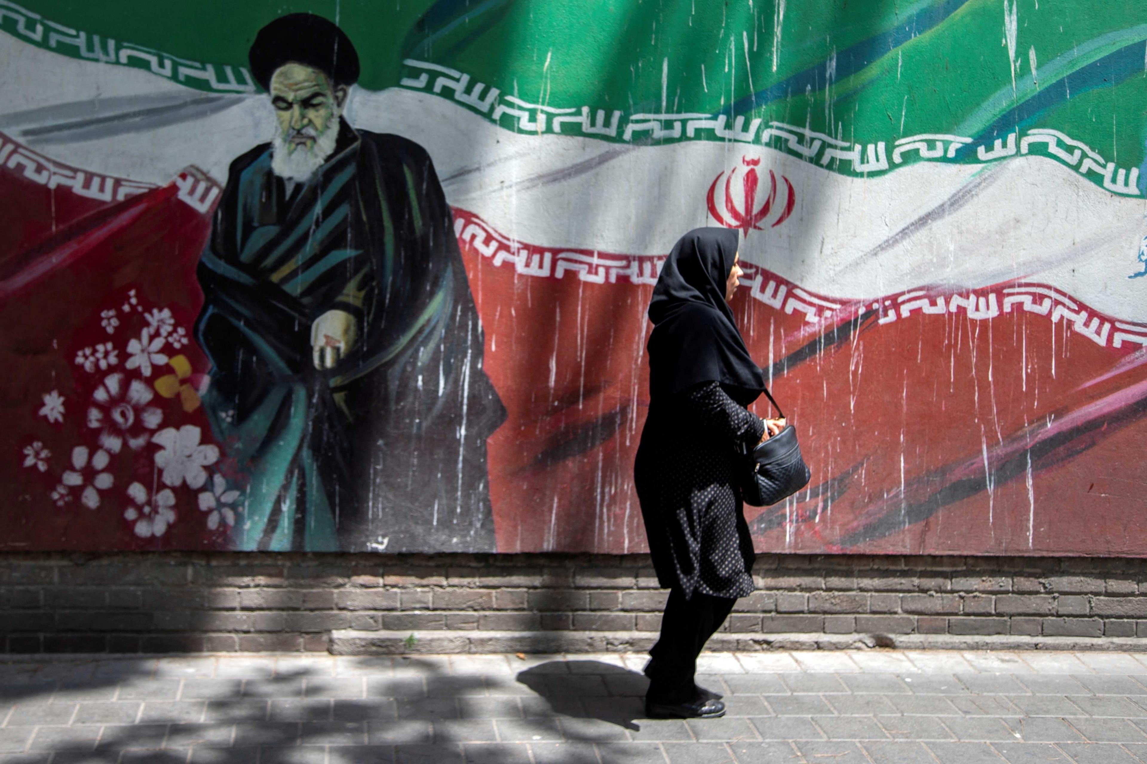An Iranian woman walks in front of a mural in Tehran, Iran July 7, 2019. Photo: Reuters