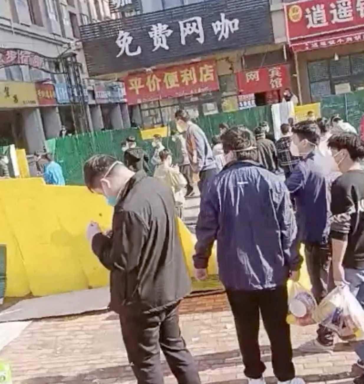 A group of people cross a downed fence following a protest at Foxconn's plant in Zhengzhou, China, in this screengrab obtained from a video released Nov 23. Photo: Reuters 