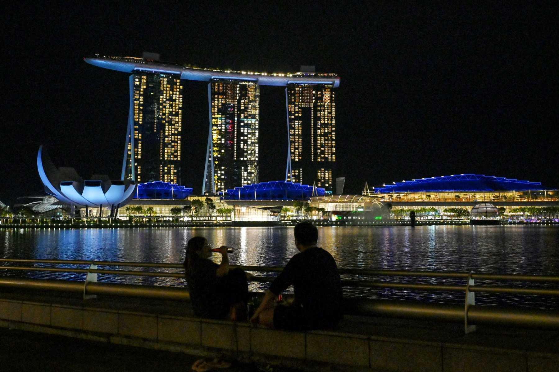 This picture taken on Oct 10, shows people sitting opposite the Marina Bays Sands hotels and resorts in Singapore. Photo: AFP 