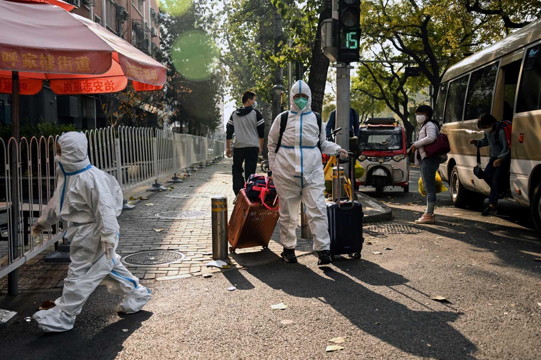People wearing personal protective equipment walk along a street in Beijing on Nov 23, amid a lockdown due to Covid-19 coronavirus restrictions. Photo: AFP 