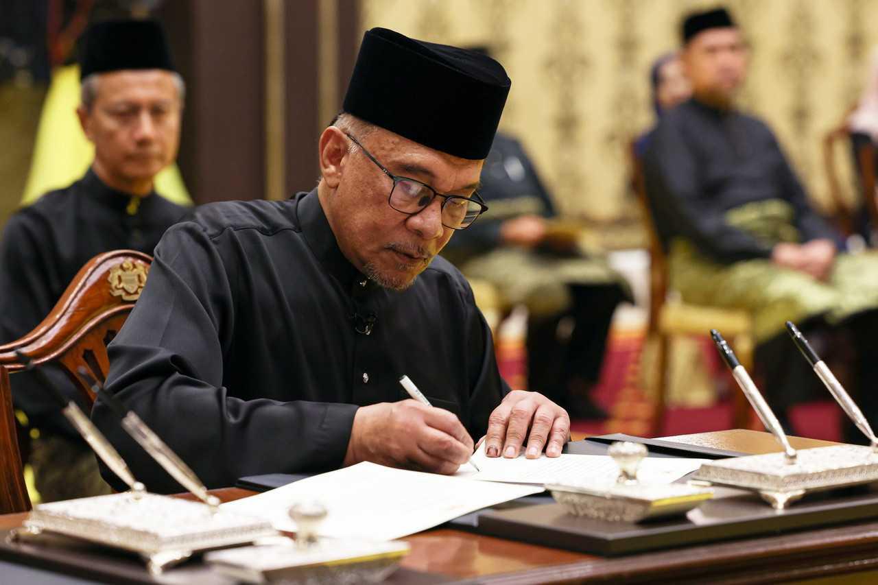 Pengerusi Pakatan harapan Anwar Ibrahim menandatangani surat pengesahan jawatan ketika upacara mengangkat sumpah sebagai perdana menteri di Istana Negara hari ini. Gambar: Bernama