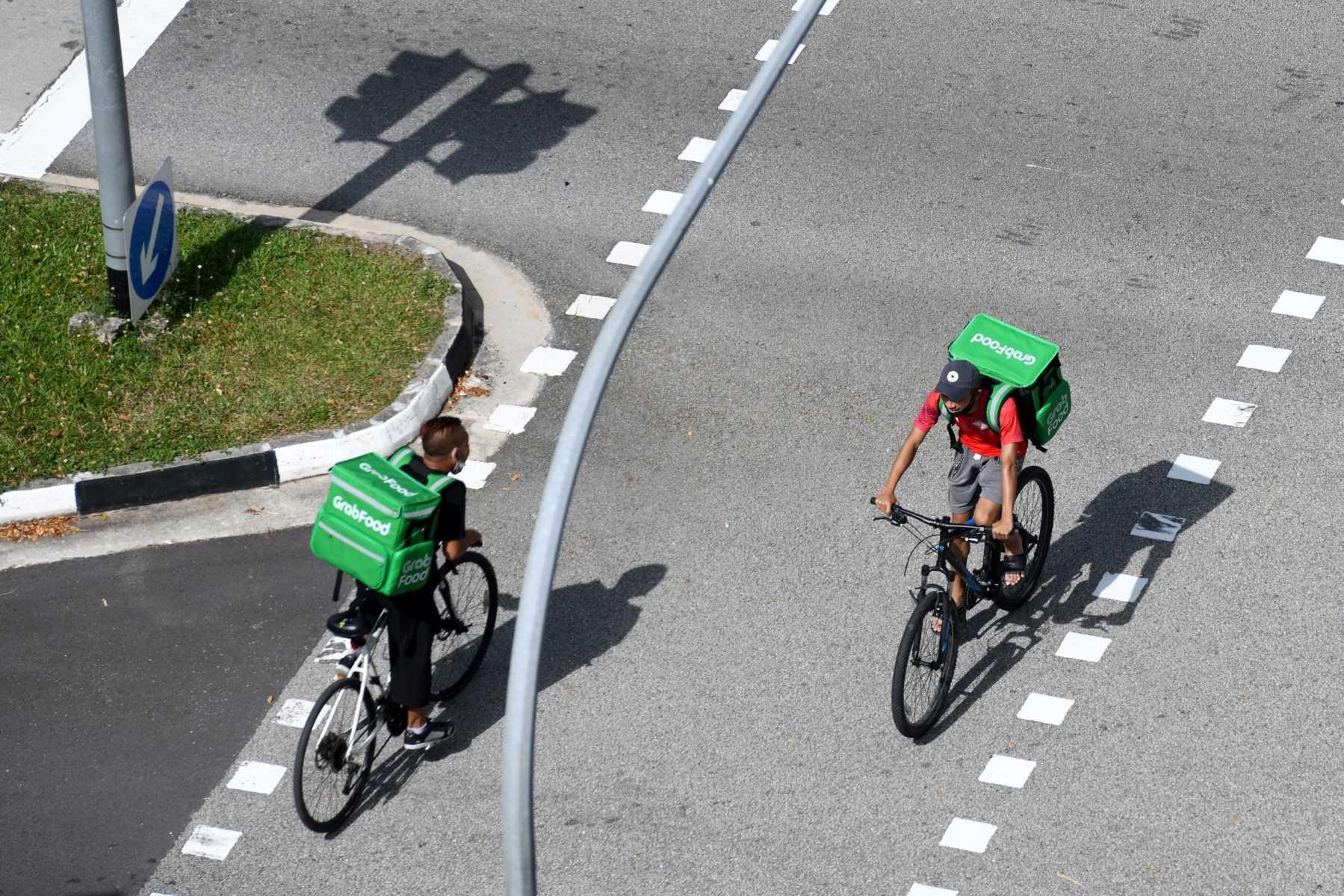 Grab delivery cyclists ride past eact other in Singapore on April 20, 2020. Photo: AFP