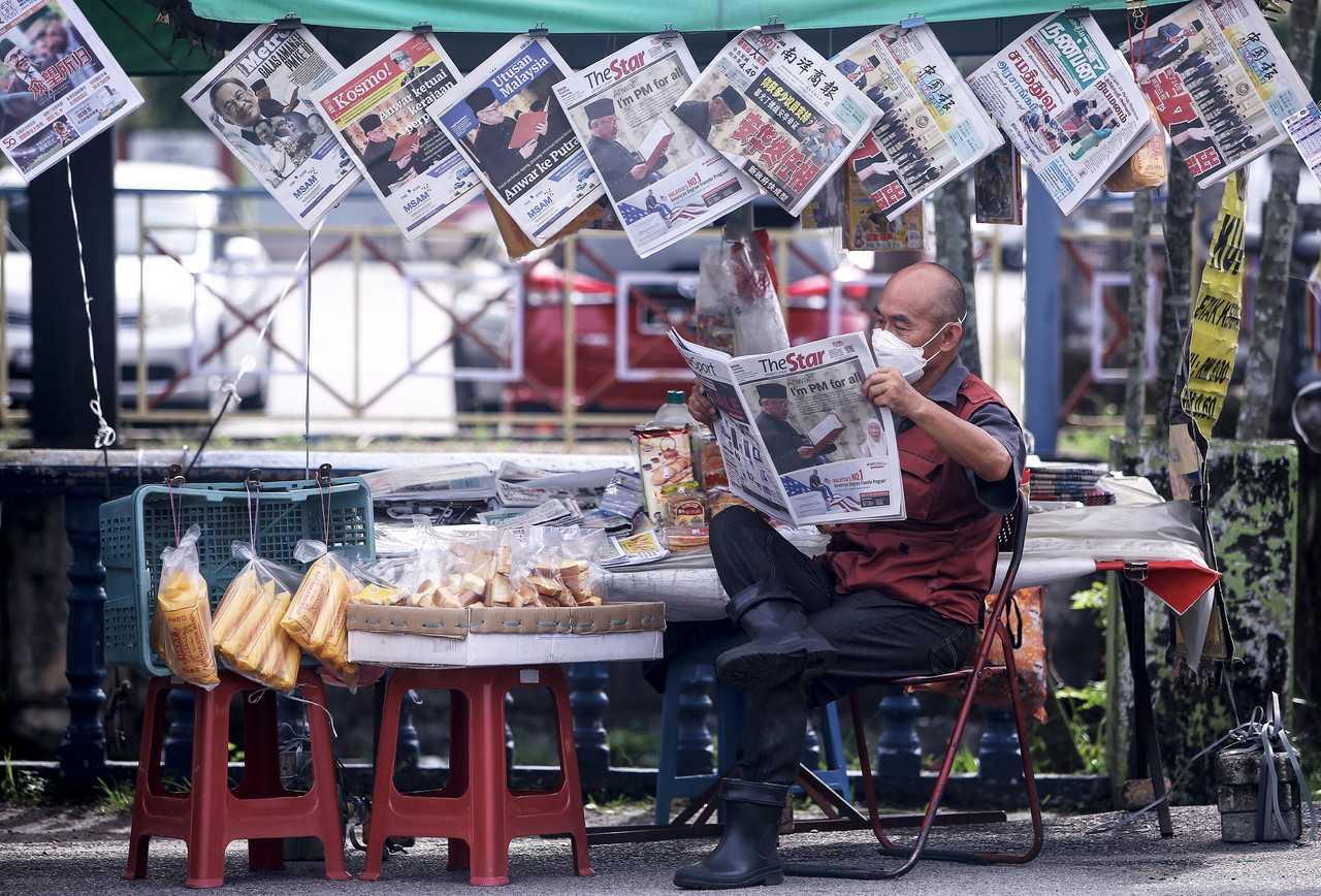 A newspaper vendor reads the headlines about Anwar Ibrahim being sworn in as prime minister in Port Dickson today. Photo: Bernama
