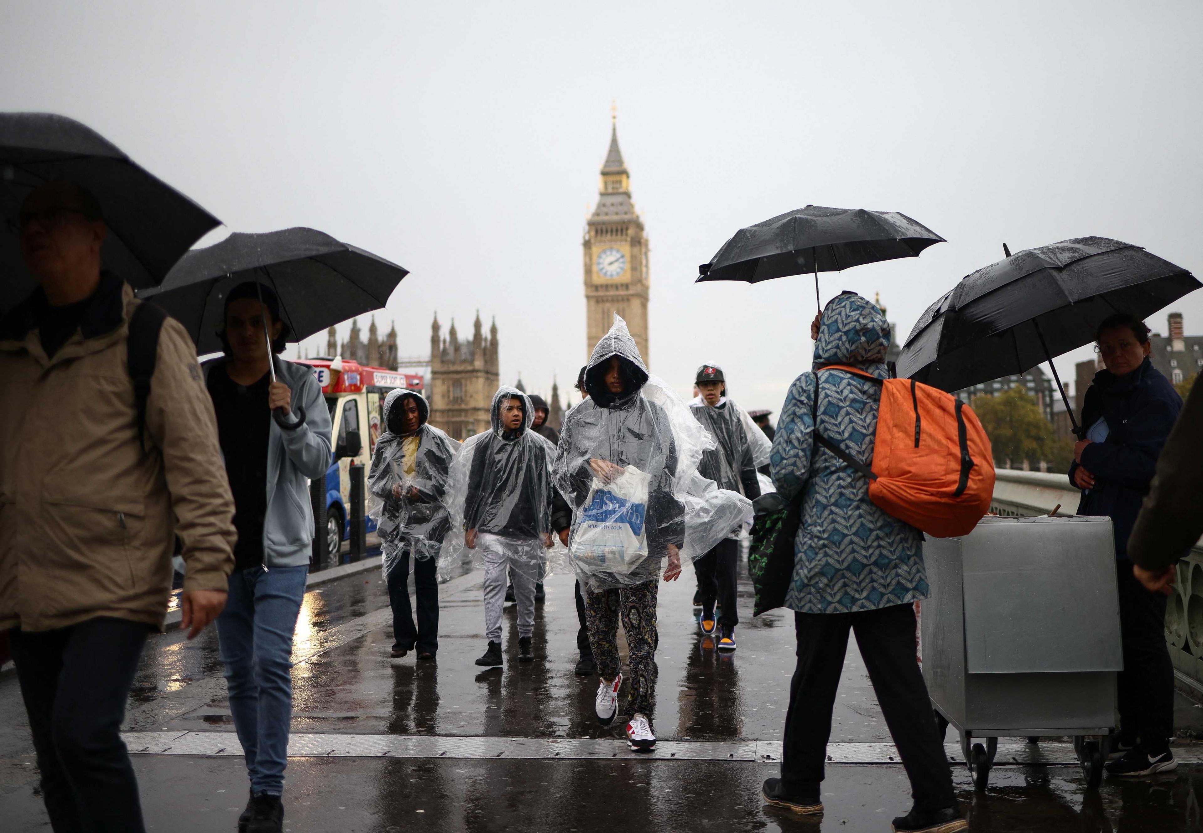 Orang ramai berjalan di atas Jambatan Westminster semasa hujan lebat di London, Britain, 6 November. Gambar: Reuters