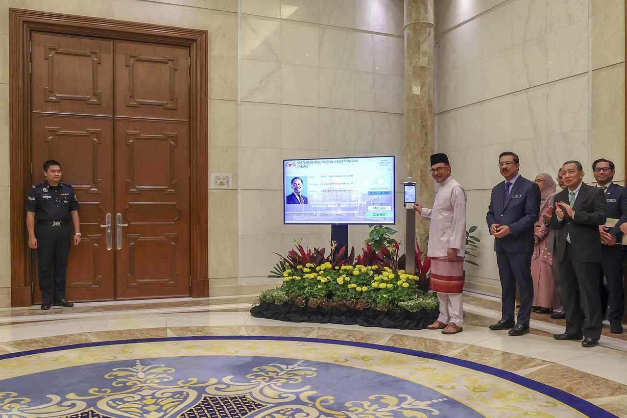 Prime Minister Anwar Ibrahim punches in with his time card on his first day of duty at Perdana Putra in Putrajaya today. Photo: Bernama