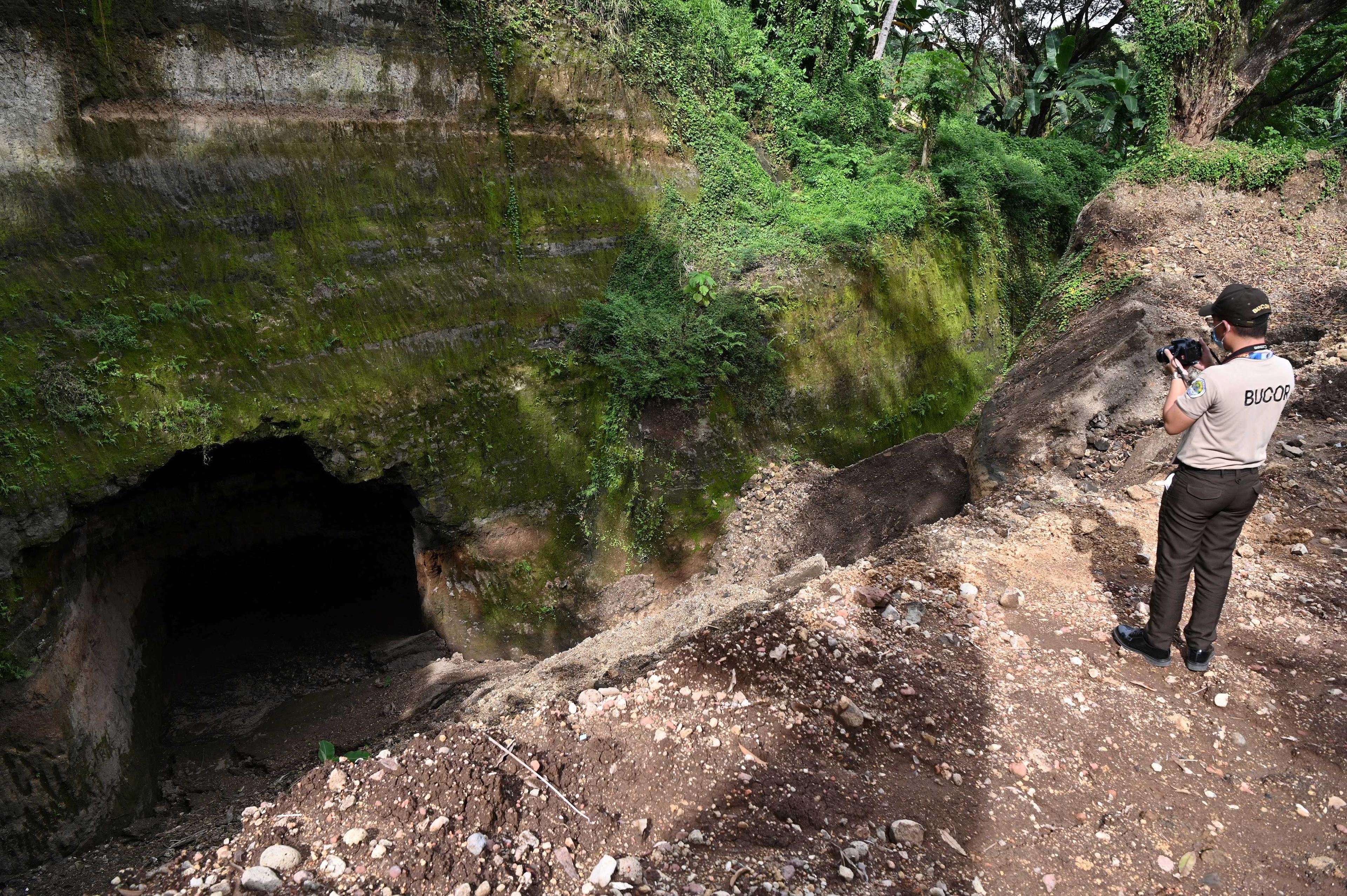 This photo taken on Nov 23, shows a bureau of corrections officer taking photos of a large pit near the official quarters of the country's prisons chief at the New Bilibid Prison facility in Muntinlupa City, suburban Manila. Photo: AFP