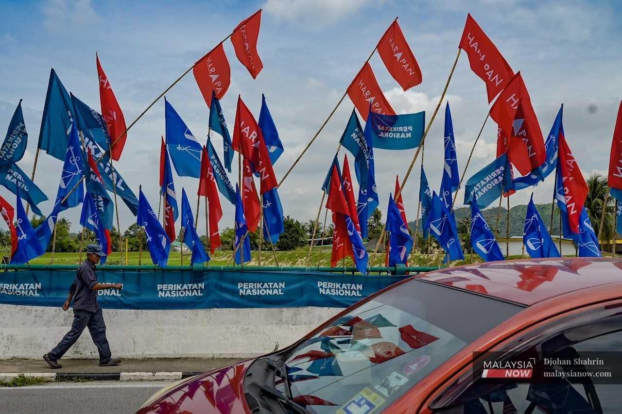 A man walks past an array of party flags ahead of the 15th general election in Tambun, Perak. 
