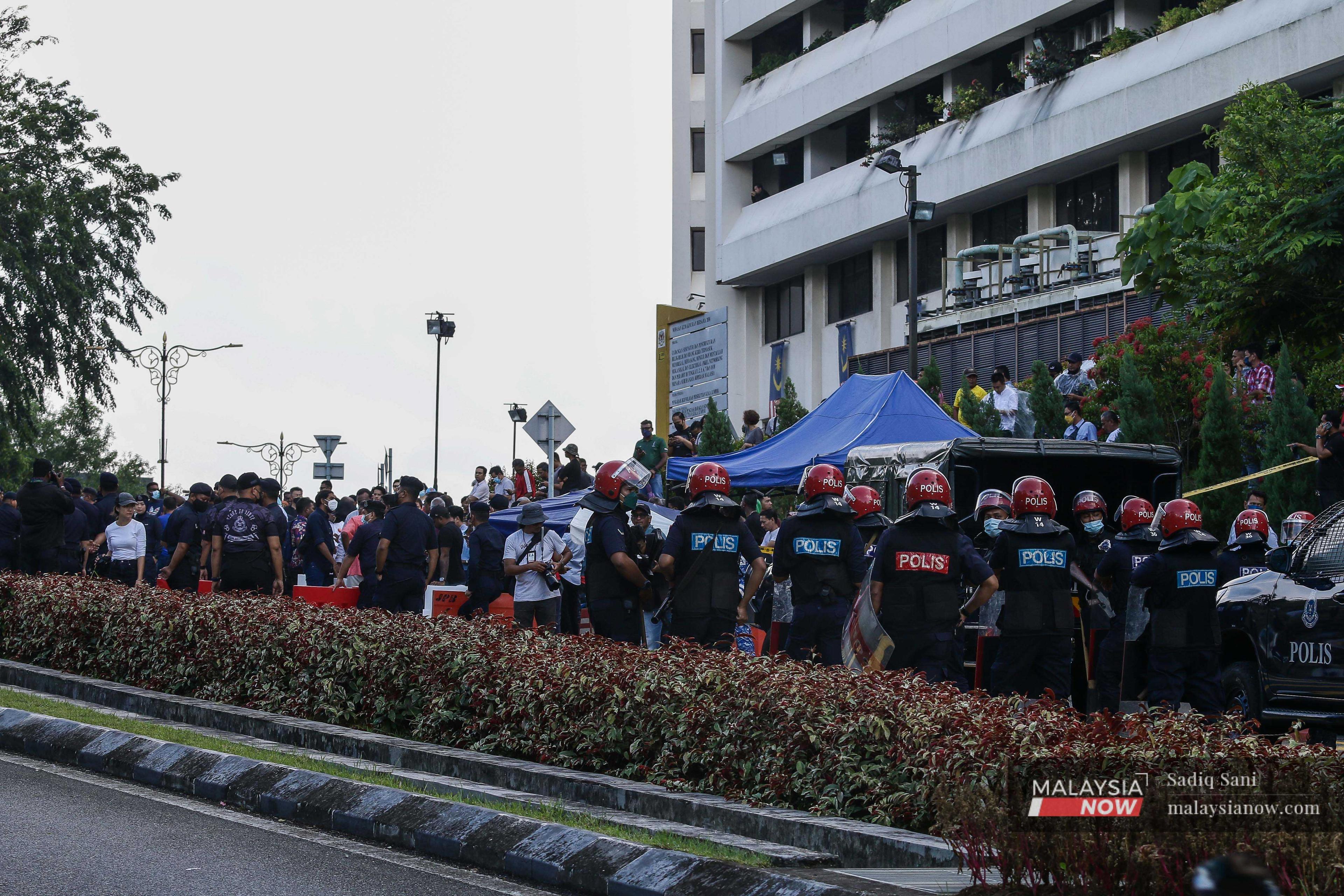 Members of the police Federal Reserve Unit stand guard amid the crowd of Pakatan Harapan supporters outside the palace. 
