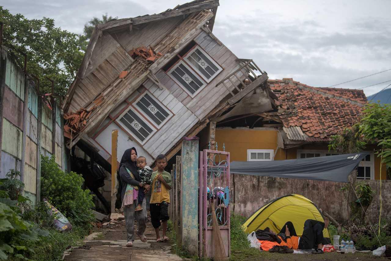 A woman carrying her child walks near a badly damaged house after Monday's earthquake in Cianjur, West Java province, Indonesia, Nov 25, 2022, in this photo taken by Antara Foto. Photo: Reuters