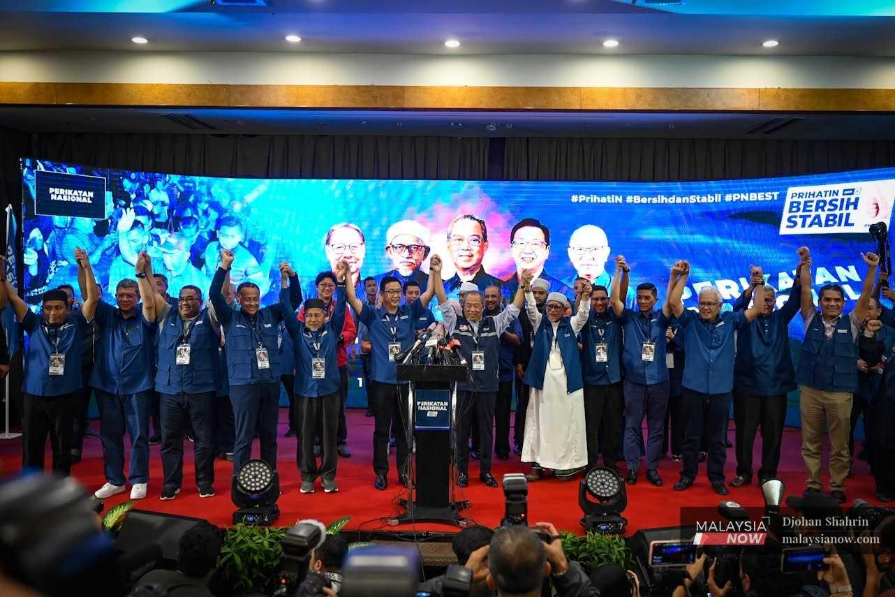 Perikatan Nasional leaders including their chairman Muhyiddin Yassin raise their hands after the results of the election showing their victory in 73 seats, in Glenmarie, Shah Alam. 