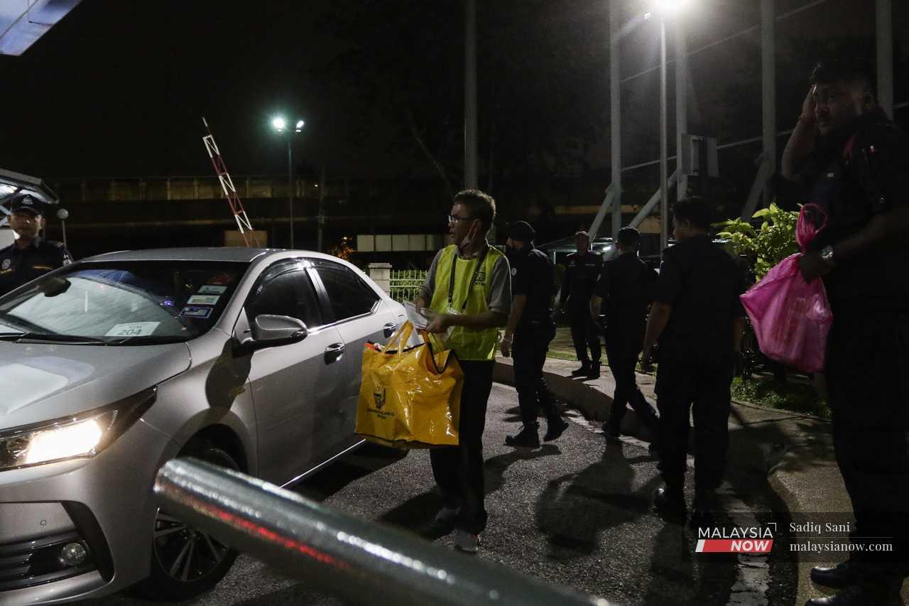 An Election Commission officer carries a ballot box from the car to a vote counting centre in Subang after voting ends on Nov 19. 