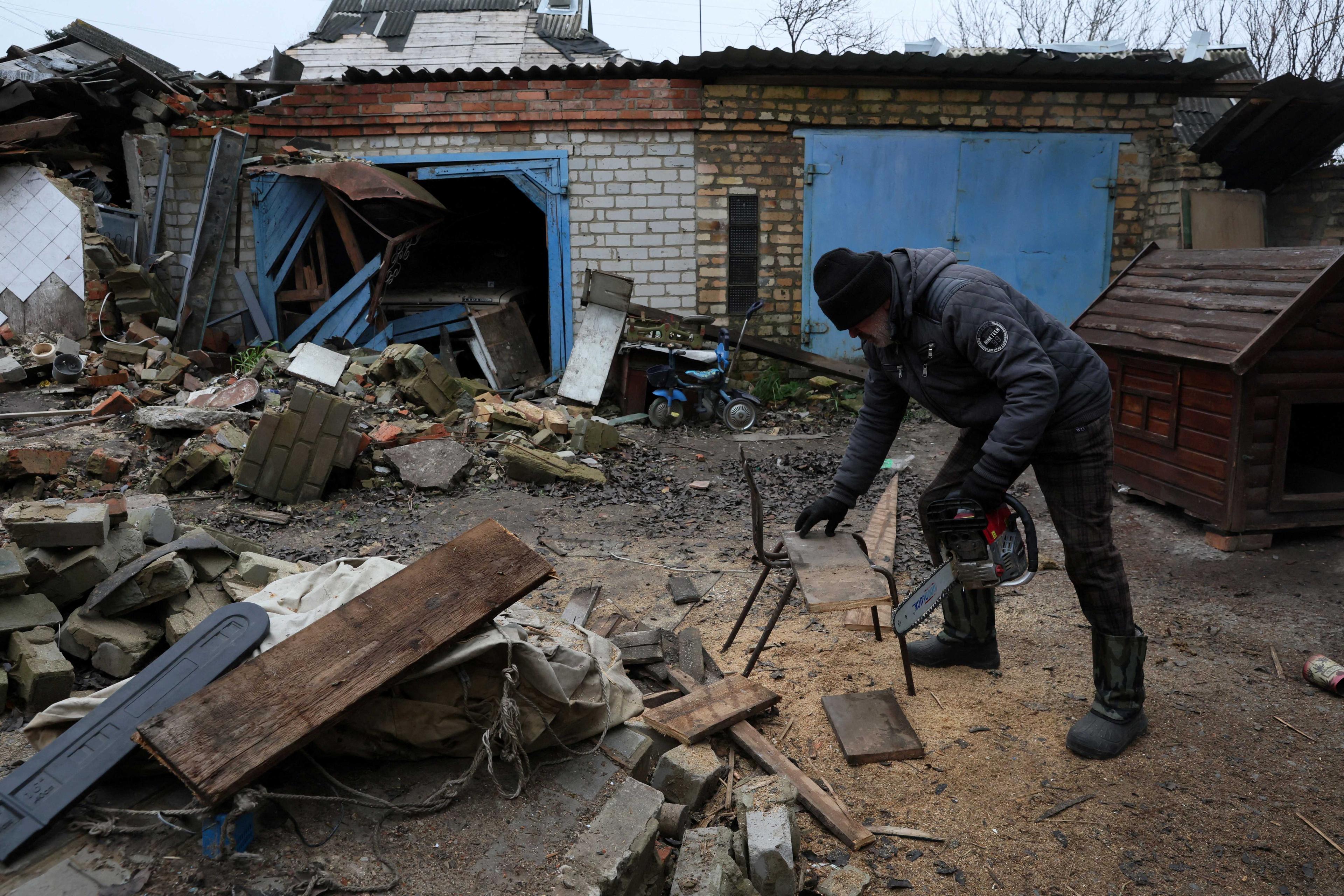 A man cuts a plank of wood into smaller pieces for firewood on his land in Siversk, Donetsk region, Ukraine, Nov 28. Photo: Reuters
