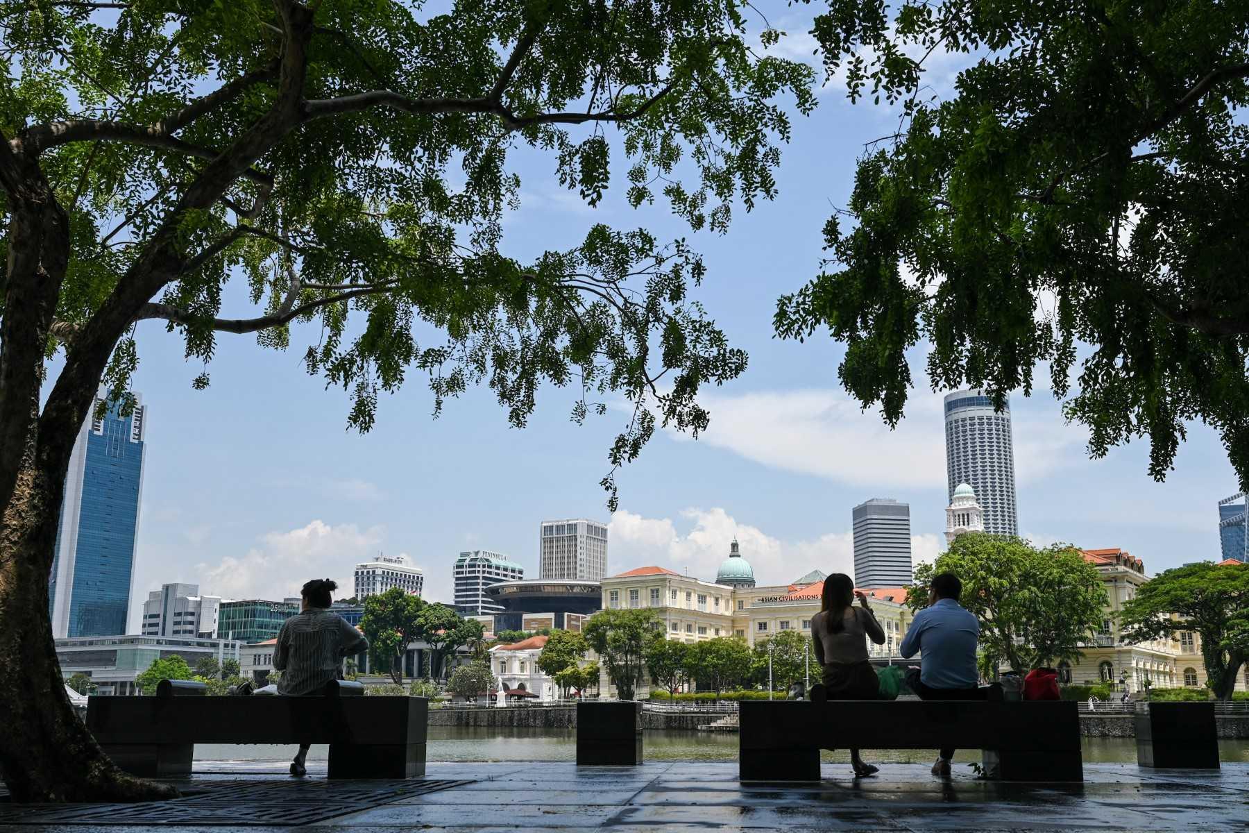 People sit on benches during lunch time opposite the Parliament building in Singapore on Oct 20. Photo: AFP