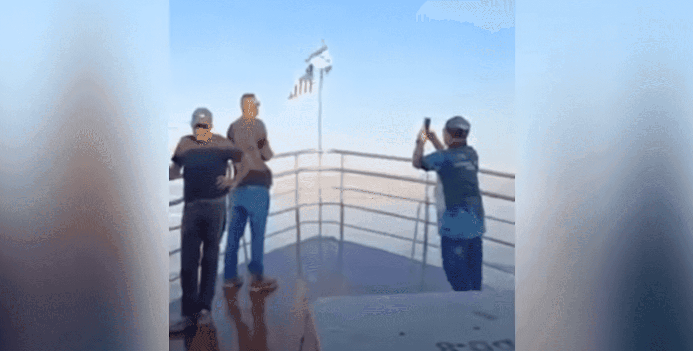 A screenshot of a video showing a group of people singing Negaraku alongside the flags of Malaysia and Israel.