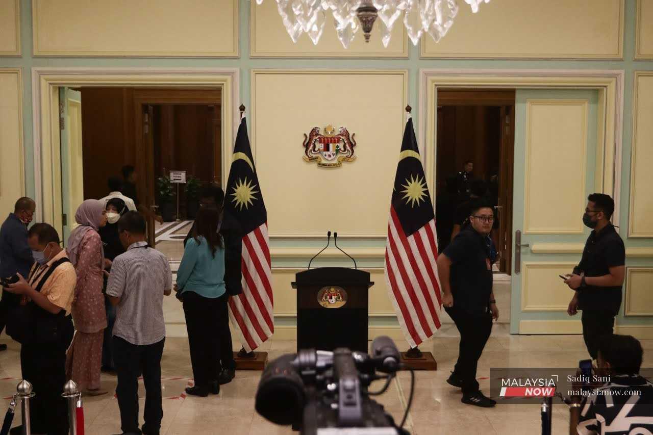 Reporters wait near the empty podium for Prime Minister Anwar Ibrahim's press conference at Perdana Putra in Putrajaya today.