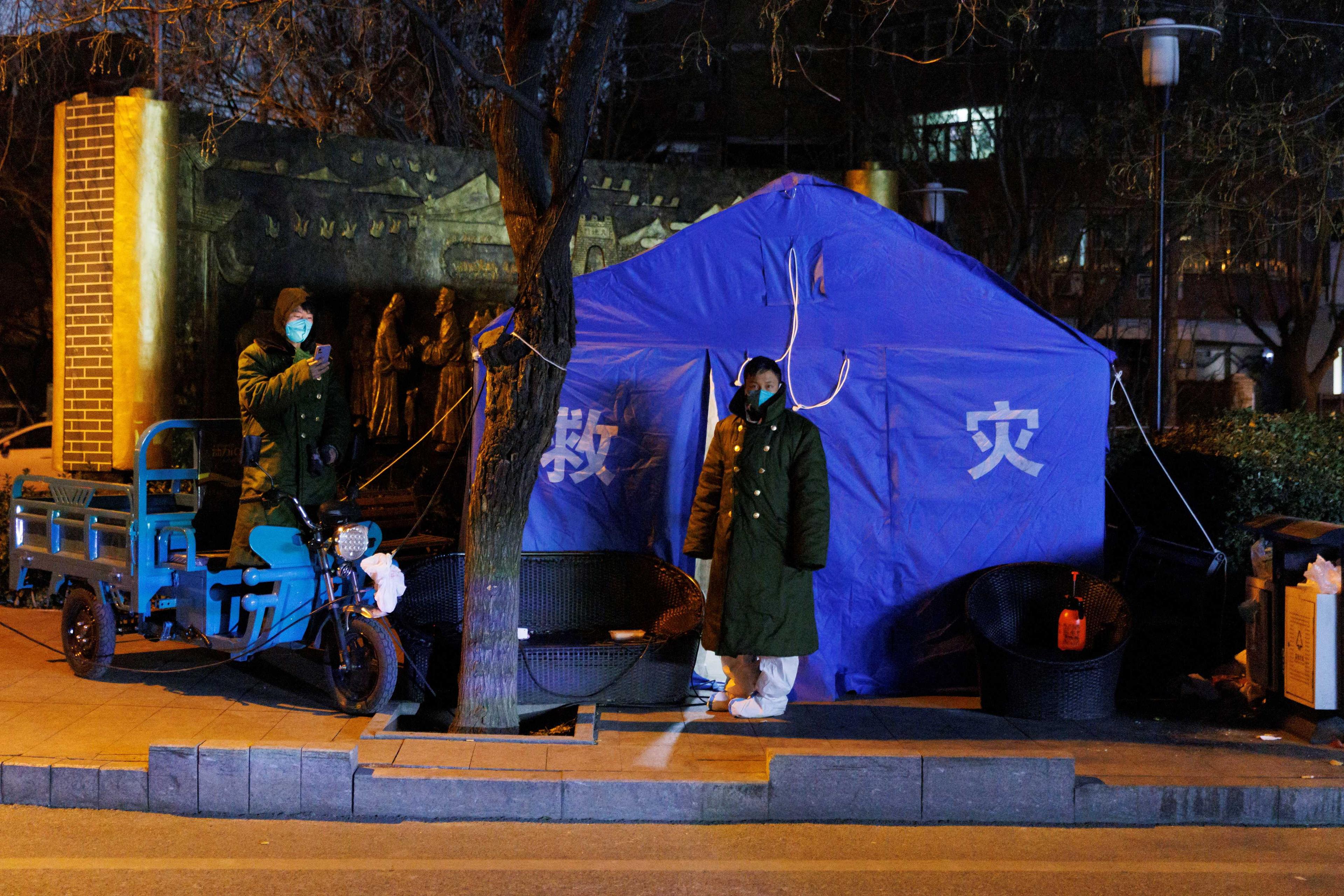 A pandemic prevention worker wears a winter coat over his protective suit as he stands outside a tent that serves as his living quarter as Covid-19 outbreaks continue in Beijing, Dec 4. Photo: Reuters