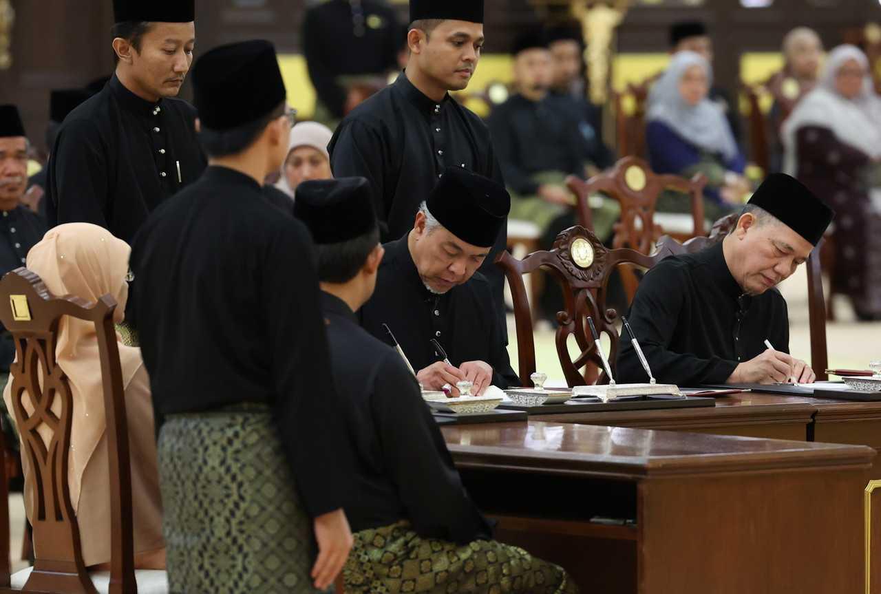 Umno's Ahmad Zahid Hamidi and Fadillah Yusof of Gabungan Parti Sarawak sign their instruments of appointment as deputy prime ministers at their swearing-in ceremony as Cabinet members at Istana Negara on Dec 3. Photo: Bernama