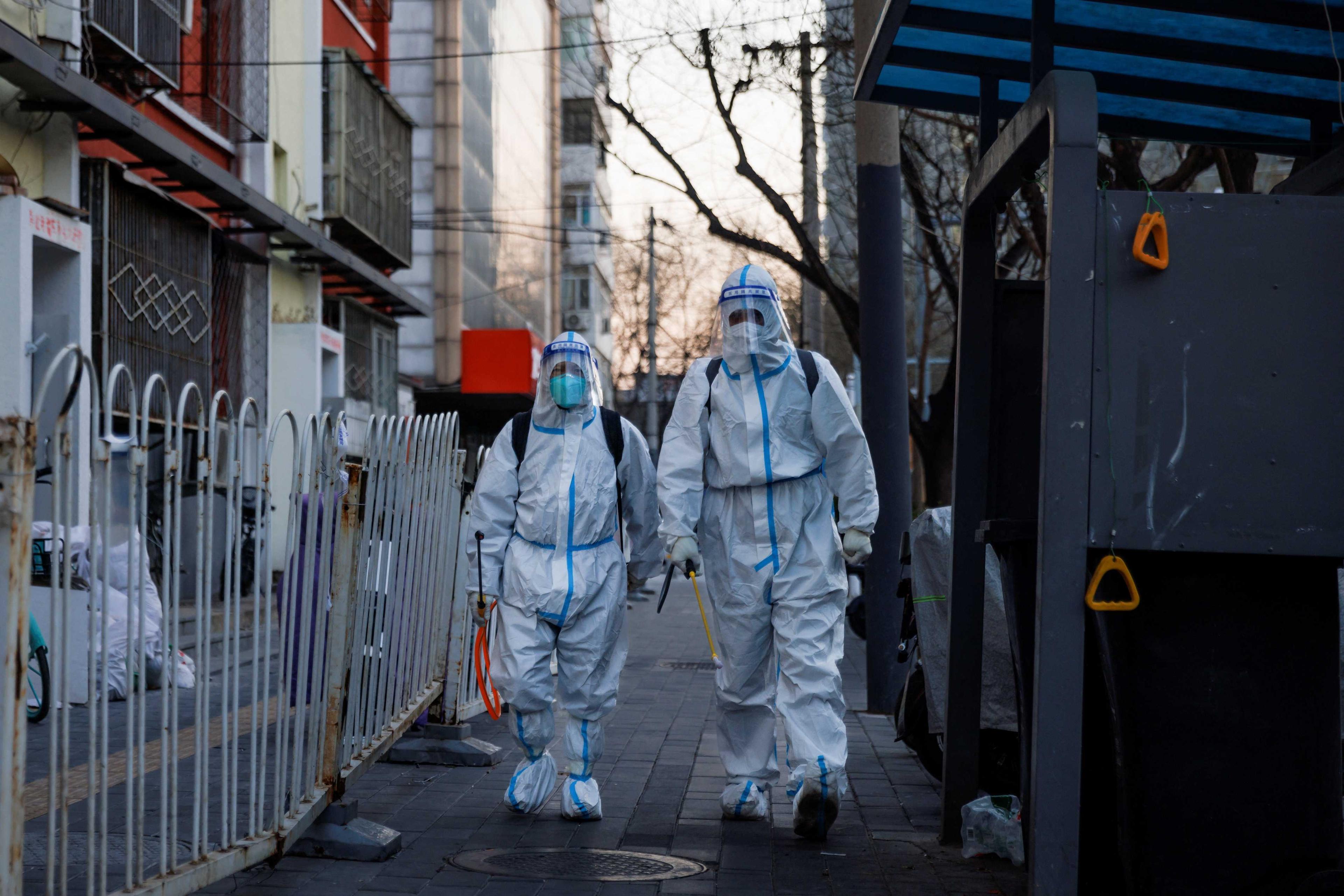 Pandemic prevention workers in protective suits walk in a street as Covid-19 outbreaks continue in Beijing, Dec 4. Photo: Reuters
