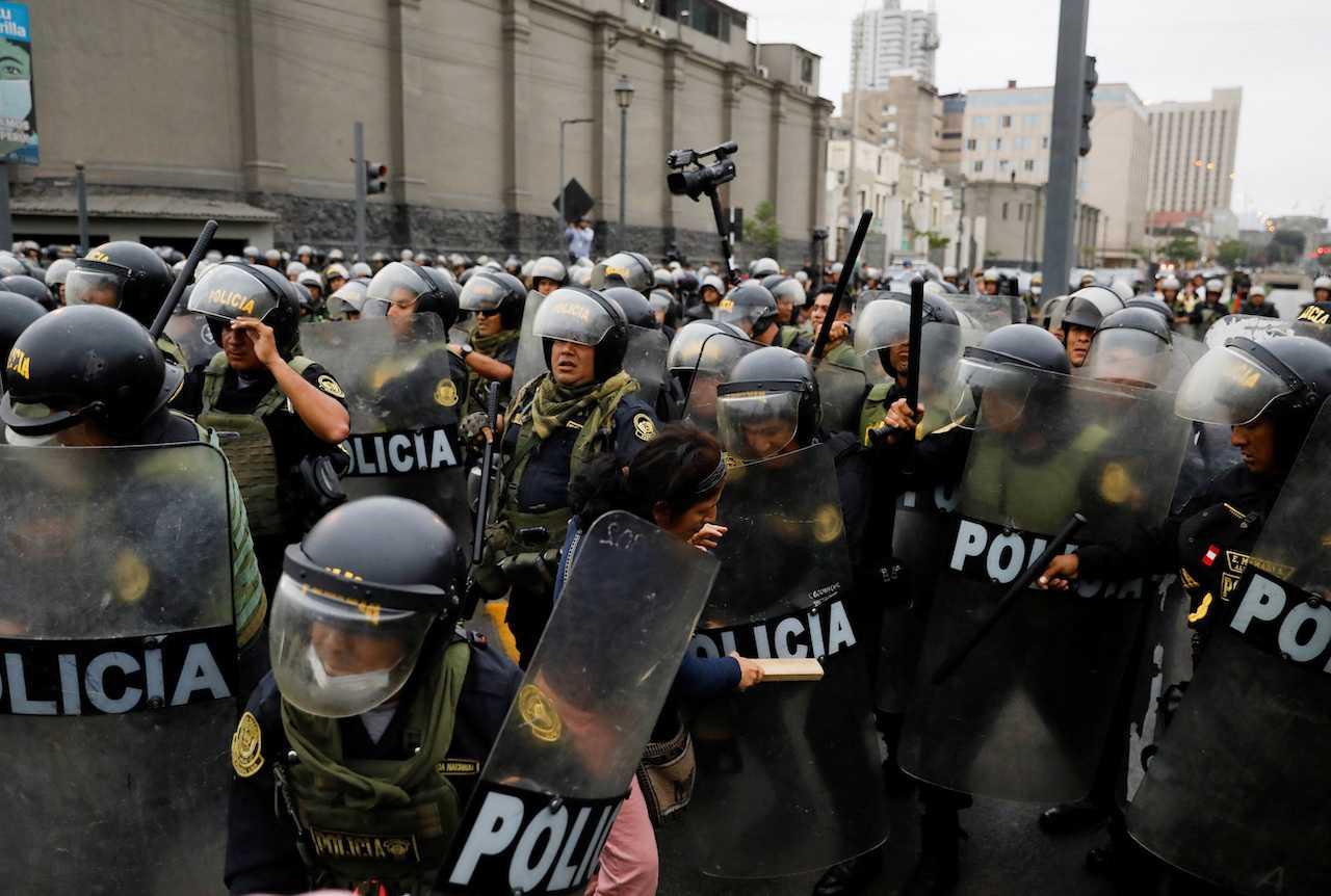 Police officers clash with a demonstrator near Lima's Prefecture where President Pedro Castillo was reportedly staying, after Congress approved the removal of Castillo, in Lima, Peru, Dec 7. Photo: Reuters
