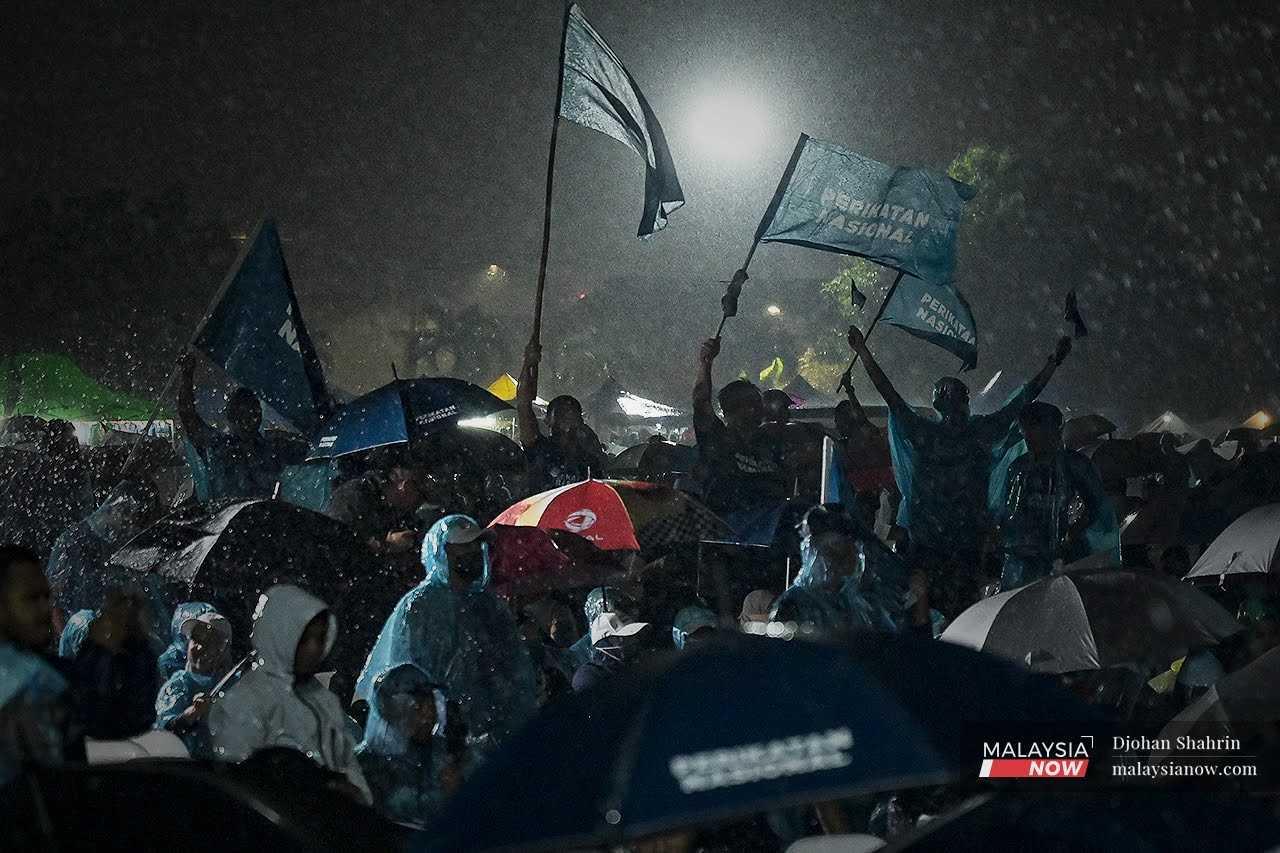 Perikatan Nasional supporters wave flags in the rain at an election gathering in Kuala Lumpur on Nov 14. 
